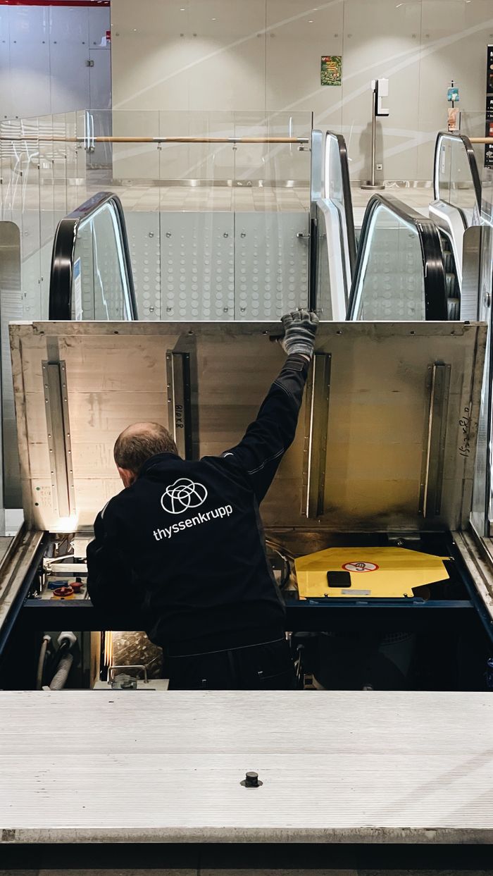 our-experience A maintenance technician working on an indoor escalator in Trekhgorka, Russia.